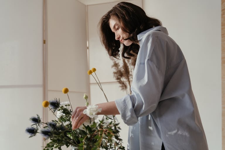 A florist carefully arranging a bouquet with craspedia and eucalyptus.